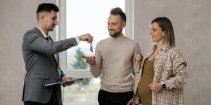 un couple de jeunes avec un agent immobilier qui leur remet les clés de leur maison