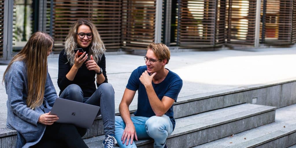 trois étudiants assis sur des marches en train de discuter